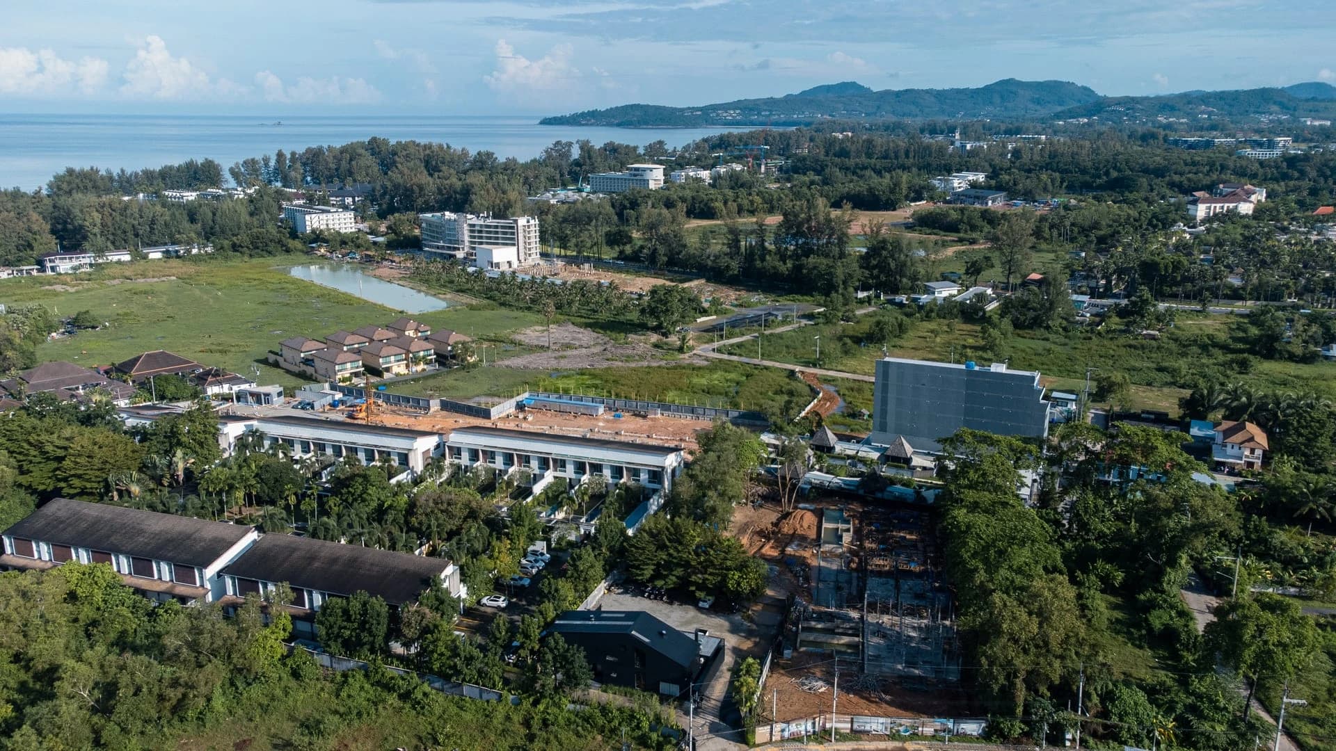 Foto con dron sobre Cherng Talay hacia la bahía de Bang Tao y el mar de Andamán, resorts de poca altura en primer plano