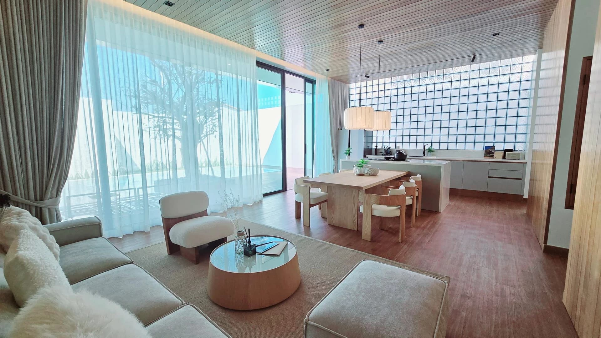 Living room of the show villa: sofa, coffee table and a full-height glass-block wall diffusing daylight